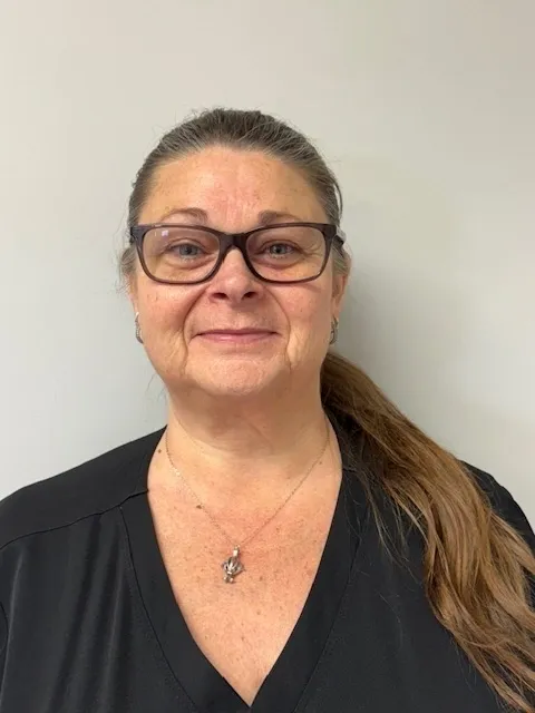 Woman with glasses and long ponytail smiling.